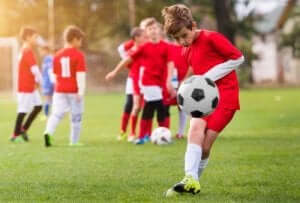 En gutt i et ungdomsfotballag som sparker en ball.