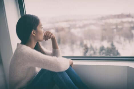 En deprimert kvinne som ser ut av vinduet på en overskyet dag.
