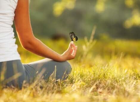 En kvinne som mediterer med en sommerfugl på fingeren