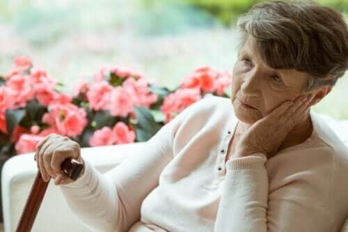 En gammel kvinne med Alzheimers som sitter og ser ut i luften.