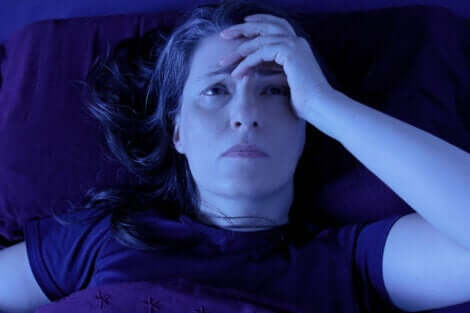 En kvinne i sengen med hodepine.