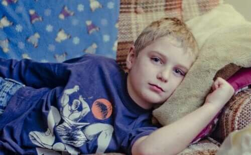 En trist gutt som ligger på sofaen.