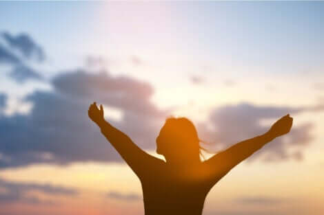 En kvinne med åpne armer som tenker på om bevissthet er et produkt av hjernen.