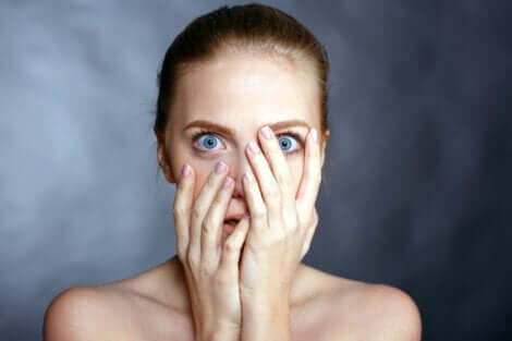 En kvinne med blå øyne som dekker til ansiktet.