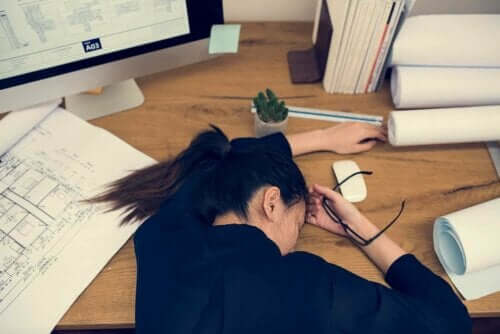 En kvinne som sover på skrivebordet sitt.