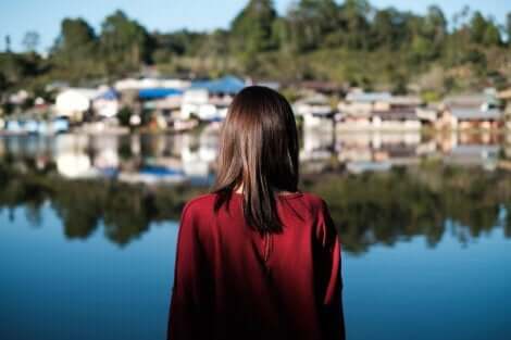 En kvinne som ser over en innsjø mot en liten landsby.
