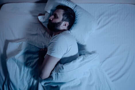 En sovende mann på siden i sengen.