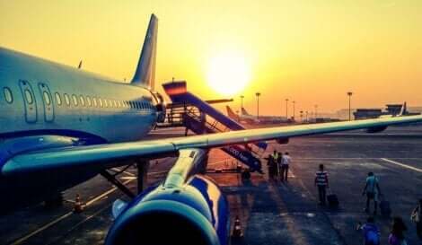 Folk som går ombord på et fly ved solnedgang.