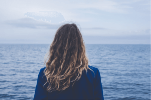 Kvinne som ser ut mot havet.