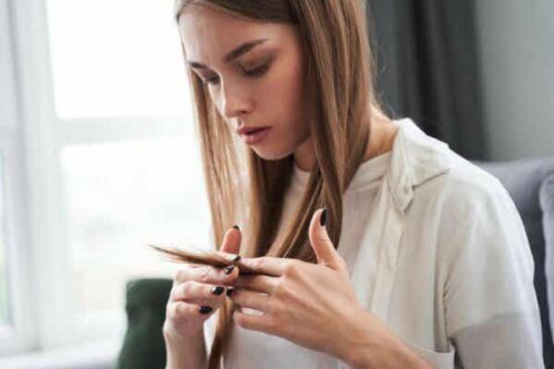 En kvinne som ser på håret sitt.