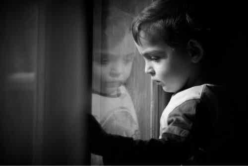 Et trist barn som ser ut av vinduet.
