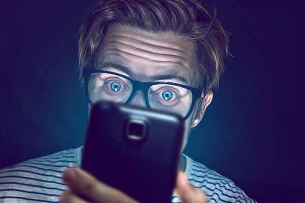 En mann som ser på en telefon som viser morbid nysgjerrighet