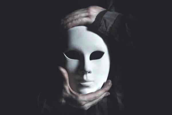 Hender som holder en maske